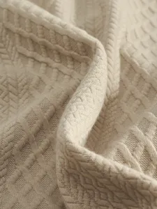 Close-up detail of premium beige jacquard knit fabric showing fine texture and soft drape quality.