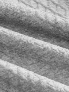 Close-up detail of soft grey jacquard fabric texture, showing fine knit pattern clearly.