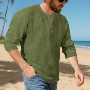 Close-up shot of men's textured green long-sleeve Henley shirt with button placket on beach.