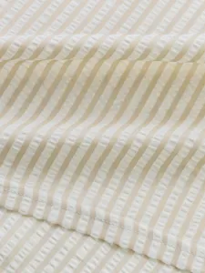 Close-up detail of striped seersucker fabric in beige and white for stylish summer shirts.