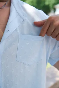 Gros plan sur la chemise jacquard bleu clair pour homme, poche poitrine et col.