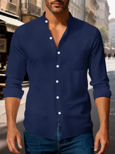 Close-up of the mandarin collar, white buttons and chest pocket on a navy blue linen shirt.