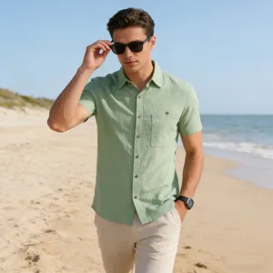 Detail view of the light green linen short sleeve shirt worn comfortably on the beach.