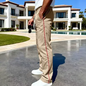 Detailed view of casual men's khaki sweatpants with red side stripe and loose fit.