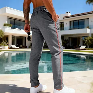 Detail view of men's casual grey sweatpants featuring red side stripes and relaxed fit.