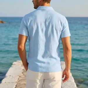 Detail shot of a light blue linen short sleeve polo shirt worn by a man at the seaside pier.