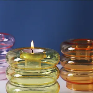 Close-up of yellow glass candle holder with lit tea light on blue background