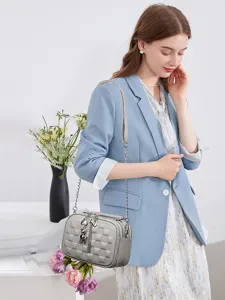 Detailed view of the elegant grey checkered soft leather women cross-body bag worn by model.