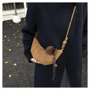 Sac bandoulière croissant en daim marron rétro, détail chic pour sac porté épaule d'automne.