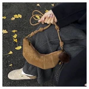 Vue détaillée du sac croissant rétro marron dans une scène d'automne avec des feuilles.