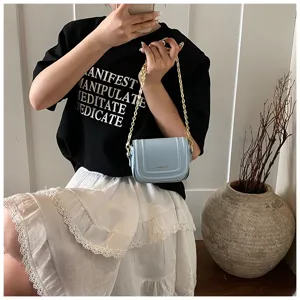 Detailed view of a stylish light blue crossbody bag with gold chain strap held by model.