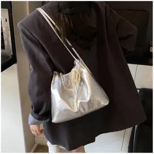 Close-up detail of the stylish silver metallic shoulder bag with pearl pendant, elegant strap.