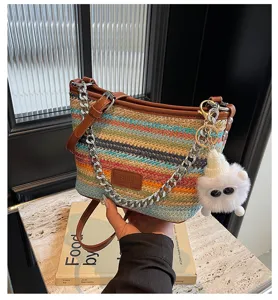 Colorful woven straw bucket bag with chain strap and cute plush charm keychain detail.