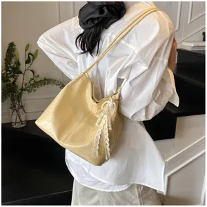 Close-up detail of the stylish yellow shoulder bag featuring a pearl lace bow for daily commute.