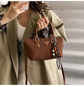 Vista dettagliata della borsa a mano in velluto a coste marrone con ciondolo di perle donna.