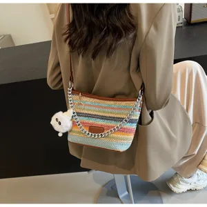 Detailed view of colorful straw woven bucket bag featuring metal chain and cute furry pendant.