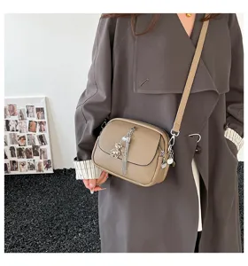Detailed view of women's PU leather crossbody bag with tassel and cute bear charm pendant.