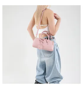 Pink cylindrical shoulder bag worn by model, showing daily styling and detailed design.