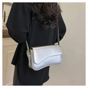 Sleek silver curved shoulder bag detail, elegant design with metal buckle, modern accessory.