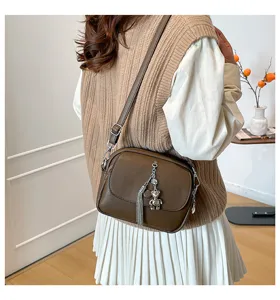 Detail shot of the brown leather crossbody bag featuring stylish tassel and cute bear charm.