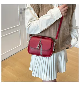 Red crossbody bag detail shot, vintage style women shoulder bag with cute bear charm and tassel.