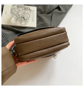 Leather crossbody bag detail view showing multi-layer design in rich brown color.