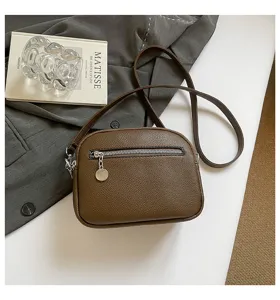Brown leather crossbody shoulder bag detailed view with front zipper pocket and metal pull.