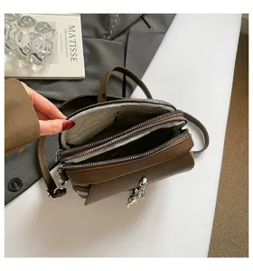 Multi-compartment brown leather crossbody bag with metal zippers, chic charm, and interior lining.