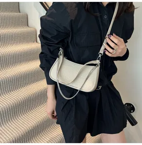 Detail shot of chic textured beige shoulder bag with metal chain on model for daily wear.