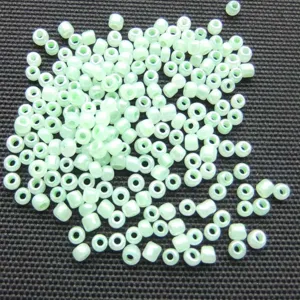 Detailed view of pale green loose seed beads for DIY handmade jewelry and craft projects.