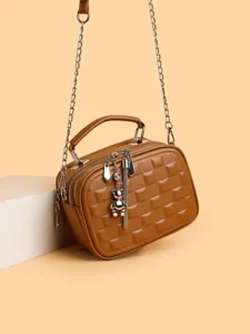 Fashionable brown quilted crossbody bag for women with metal chain strap and cute bear charm.
