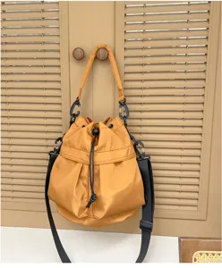 Detail shot of a stylish yellow drawstring bucket bag with black adjustable shoulder straps.