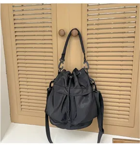 Black nylon bucket bag with drawstring closure and adjustable shoulder strap for casual daily use.