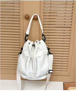 Detailed view of a stylish white bucket bag with drawstring closure and black hardware.