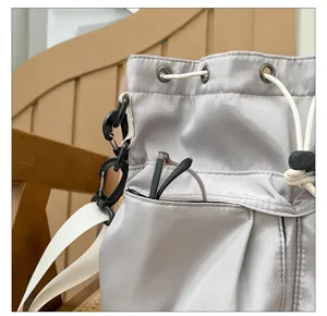 Close-up detail of light gray casual nylon bucket shoulder bag with drawstring and pocket.