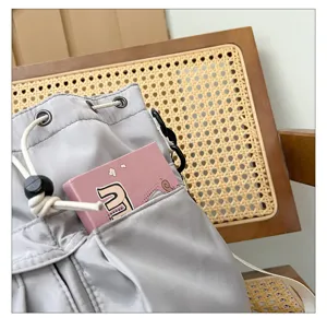 Detailed view of grey nylon drawstring shoulder bag, casual tote bag with front pocket.