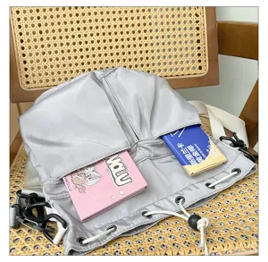 Gray nylon drawstring shoulder bag detail showing front pockets and adjustable strap design.