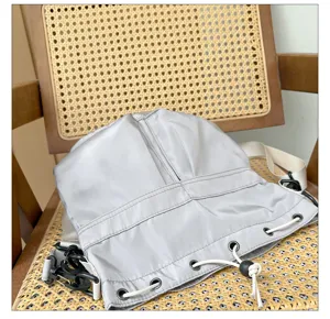 Detailed view of grey nylon shoulder bag featuring white drawstring and adjustable black buckles.