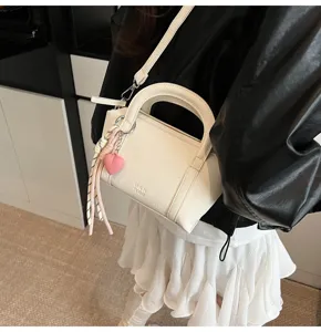 Detailed view of stylish white lychee grain pillow bag featuring a pink heart charm.