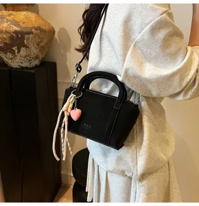 Black litchi pattern shoulder crossbody bag with cute heart charm and stylish design.