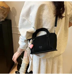 Chic black crossbody pillow bag for women, stylish shoulder bag with heart charm and handle.