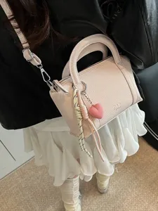 Pink lychee grain top handle pillow bag with heart charm and shoulder strap for women.