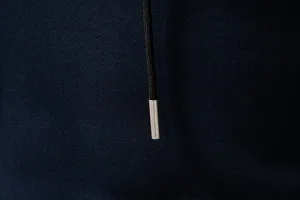 Close-up detail of men's dark blue hoodie drawstring with silver metal aglet and texture.