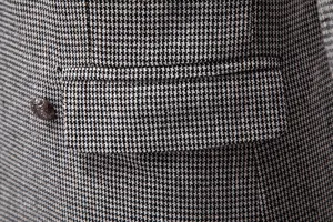 Detalle de traje ajustado de hombre, clásico patrón pata de gallo con solapa de bolsillo.