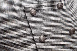 Detalle de tela de traje de hombre, patrón pata de gallo blanco y negro con botones.