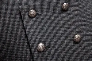 Primer plano de tela de traje para hombre con textura tweed y botones metálicos vintage de invierno.
