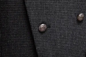 Primer plano detallado del tejido de traje de tweed gris para hombre y botones metálicos.