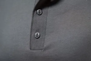 Close-up detail of grey men's henley shirt placket with buttons and textured cotton fabric.