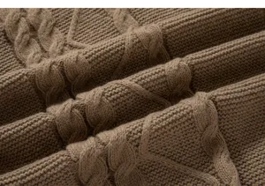 Vue en gros plan d'un tissu de pull en tricot torsadé marron, mettant en valeur la texture.