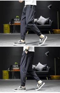 Detailed view of men casual cuffed linen harem pants worn by model, showing side fit and legs.